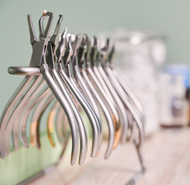 Set of various stainless steel instruments for braces in dental office. Silver removing pliers and tools for all bracket types. Concept of dentistry, orthodontics and medical instruments.